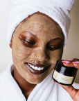 A woman looking down, wearing OBAO nourishing superfood clay mask with baobab.