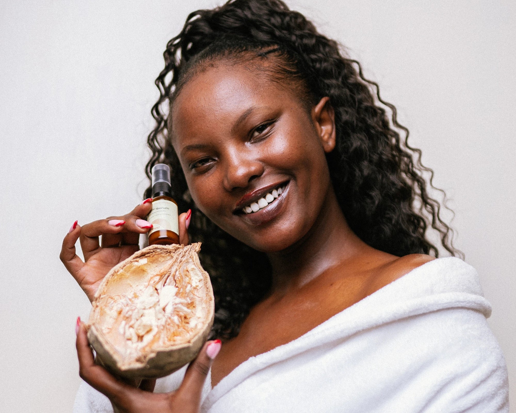 Woman presenting baobab fruit and baobab oil.